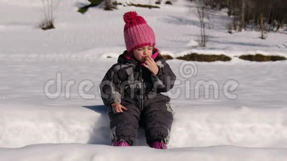旅游儿童女婴穿着雪衣在冬季乡村的高山雪道上吃小吃视频的预览图