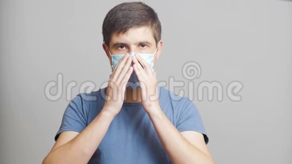 在灰色工作室背景下戴防护面具的自信青年检疫措施病毒防护视频的预览图