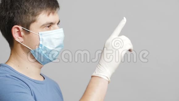 戴着医用防护面罩的人在灰色摄影棚背景下交替地指出虚拟名单上的物品医学概念视频的预览图