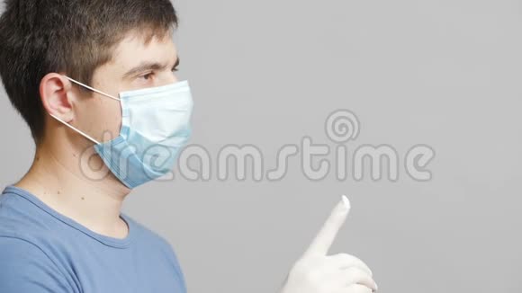 戴着医用防护面罩的人在灰色摄影棚背景下交替地指出虚拟名单上的物品医学概念视频的预览图
