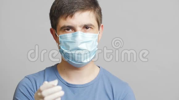 年轻的医生在灰色的工作室背景下戴着外科口罩医学和健康的概念医务工作者准备冲浪视频的预览图