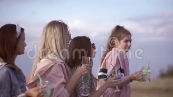 户外的女孩喝着美味的鸡尾酒叮当的眼镜跳舞玩得开心夏季城市鸡尾酒视频的预览图