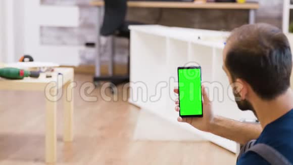 男性工人手持绿色屏幕电话的背面视图视频的预览图