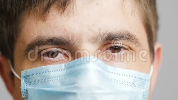 闭上眼睛看着戴着医用防护面罩的疲惫的男人看着相机看着医生看着概念医学和健康视频的预览图