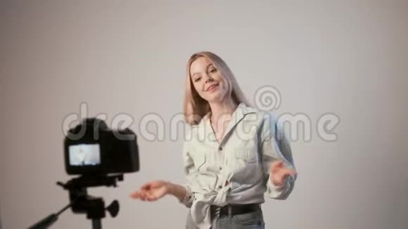 年轻女孩用三脚架上的相机录制化妆视频视频的预览图