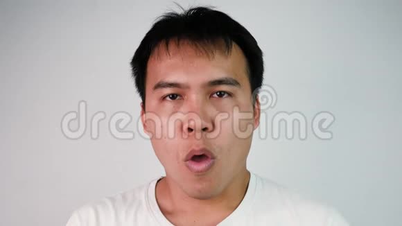 在灰色背景下一位身穿白色T恤咳嗽和喉咙痛的亚洲病人的肖像特写男性患流感视频的预览图