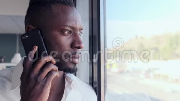 商务年轻人一边用手机说话一边透过办公室的窗户看视频的预览图