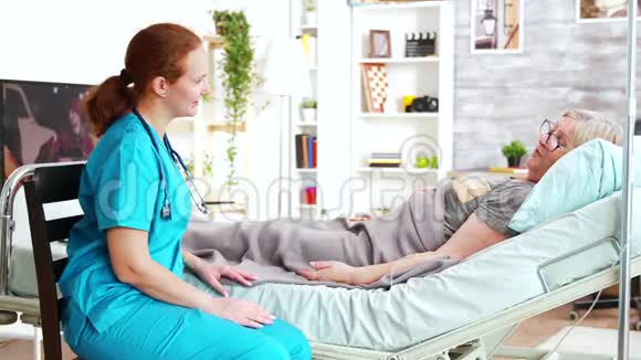 养老院的女助理牵着躺在病床上的老太太的手视频的预览图