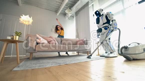 人类机器人正在打扫房间一个女人坐在沙发上视频的预览图