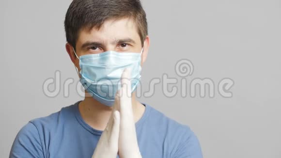 戴着幽默的外科口罩戴着灰色背景的无菌手套狡猾地搓手概念医学笑话奇怪的医生视频的预览图