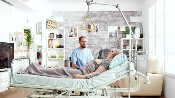养老院里的护理员和躺在病床上的一位老太太谈话视频的预览图