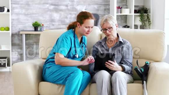 帮助老年退休妇女使用平板电脑的女护士视频的预览图