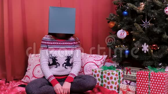 一个女人坐在圣诞树上头上戴着一个盒子节假日和新年的概念视频的预览图