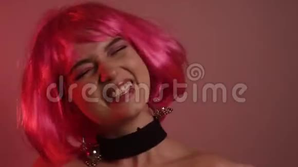 粉红色短发的女孩长粉色耳环和化妆的模特视频中的女孩笑调情摆姿势跳舞抚摸视频的预览图