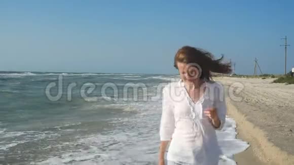穿着牛仔裤和白衬衫走在海边的女孩视频的预览图