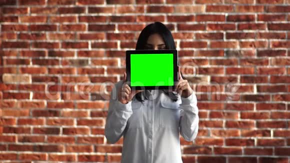 女孩拿着一个数字平板电脑脸前有一个色度在她的眼睛下面一个穿白色衬衫的少女视频的预览图
