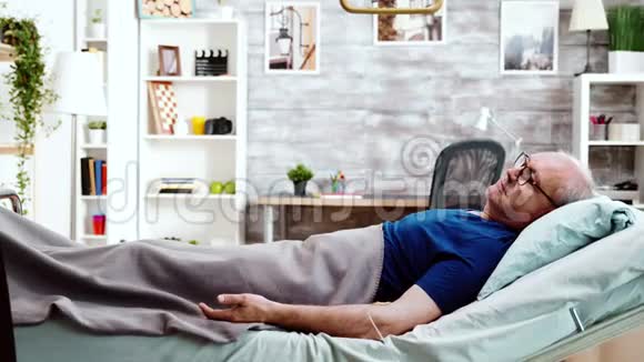 护士坐在一个躺在病床上的老病人旁边视频的预览图