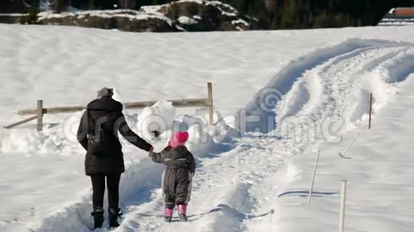 白周假期与家人母亲和婴儿从背后看到携手走在雪道后的冬天视频的预览图