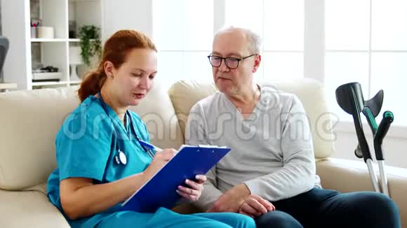 女性保健助理在舒适的养老院里记录老人的健康状况视频的预览图