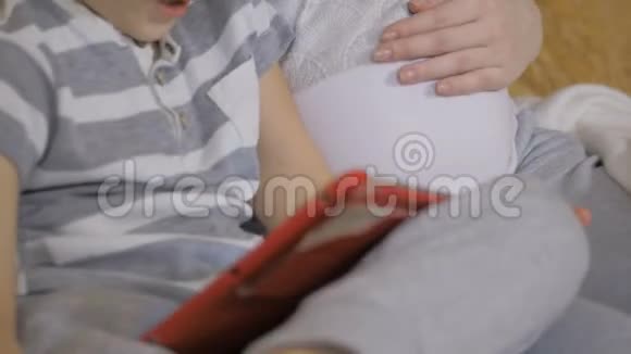 美丽的怀孕女孩和她的小儿子使用数字平板电脑并一起度过时光视频的预览图