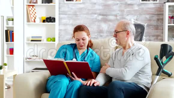 社工在养老院给一个坐在沙发上的老人和残疾人读书视频的预览图
