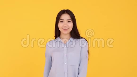 亚洲女孩表现出爱的象征用双手在黄色背景下显示心脏视频的预览图