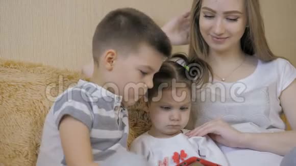 美丽的怀孕女孩和她的弟弟和小女儿使用数字平板电脑一起度过时光视频的预览图