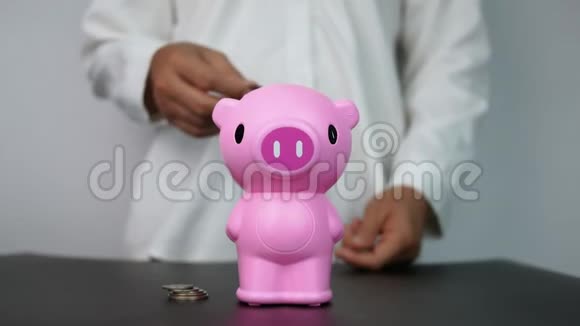 女人把硬币放进房间里的粉红色储蓄罐里省钱的概念视频的预览图