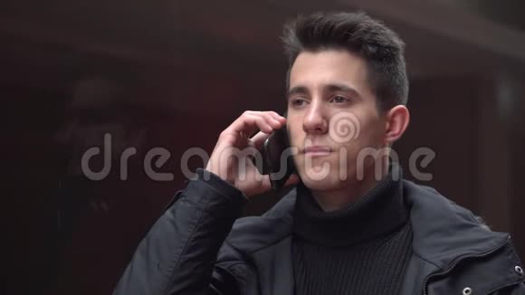 现代城市中心的英俊年轻人在街上用手机说话的肖像人和技术视频的预览图