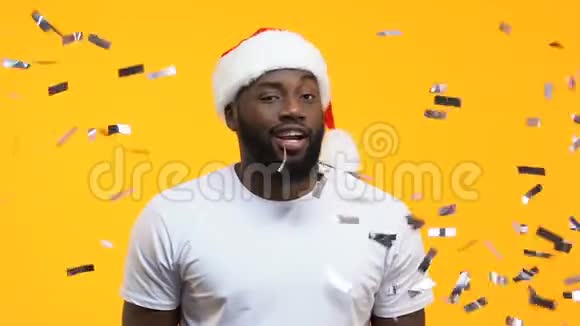 戴着圣诞帽的黑人男子在掉落的纸屑下眨眼并竖起大拇指视频的预览图