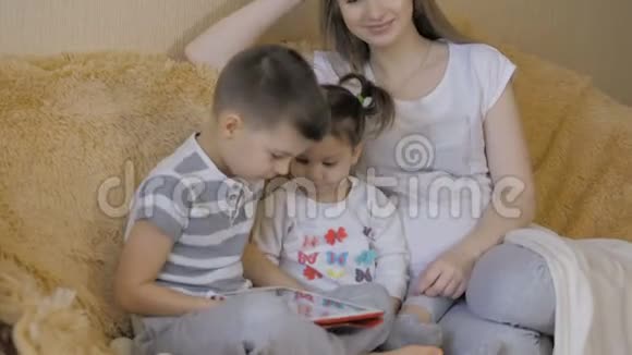 美丽的怀孕女孩和她的弟弟和小女儿使用数字平板电脑一起度过时光视频的预览图