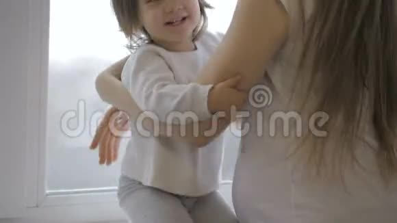 可爱的小女孩拥抱着她美丽的怀孕妈妈肚子微笑着视频的预览图