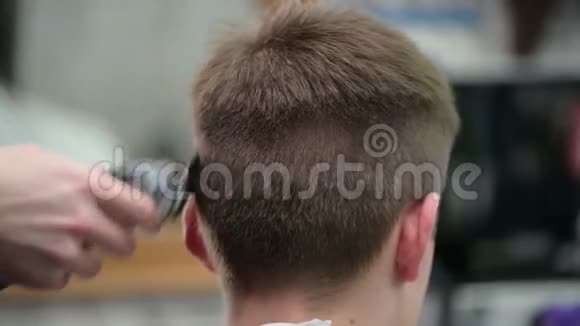 年轻人在理发店理发师父用剪子剪金发男子特写视频的预览图