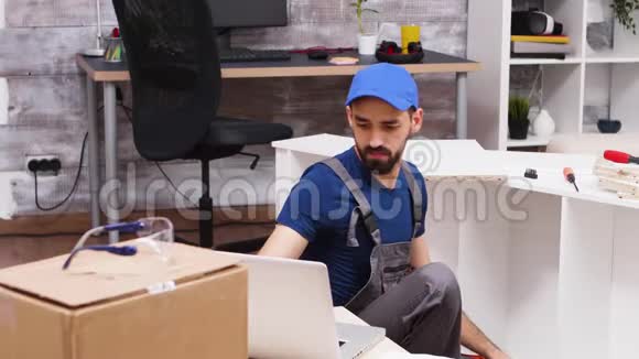 男性工人在安装架子后检查他的笔记本电脑视频的预览图