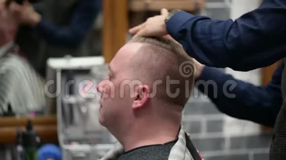 男人理发店理发整理发型大师的特写视频的预览图