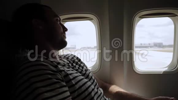 体贴的休闲男子在飞机上看着外面等待起飞视频的预览图