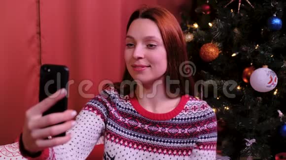 年轻女子在装饰圣诞树附近拍照假期和新年的概念视频的预览图