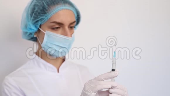 特写医生护士穿着白色医用大衣戴着手套戴着防护面具把针头插入注射器视频的预览图
