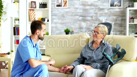 男护士牵着老妇人的手在养老院里视频的预览图