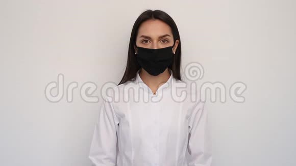 戴黑色防护面罩的年轻女护士医生把听诊器放在耳朵上医疗保健和医疗概念视频的预览图