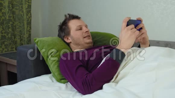 盖着毯子的人躺在床上玩手机游戏失眠观念失眠高加索人视频的预览图