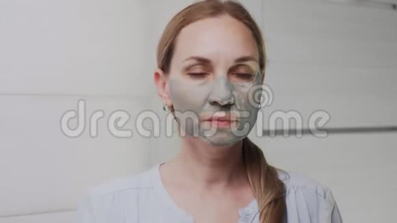 合上成年女子脸上涂着黏土面具看着镜头视频的预览图