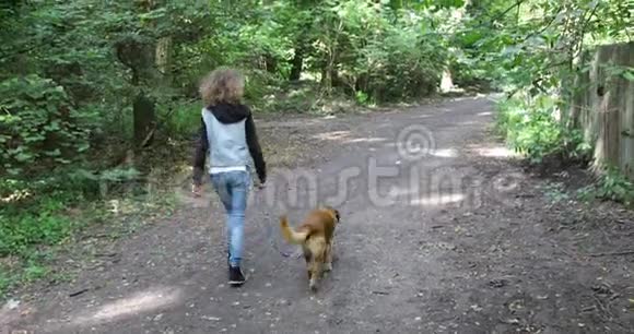 穿着牛仔裤和狗一起走路的女孩视频的预览图