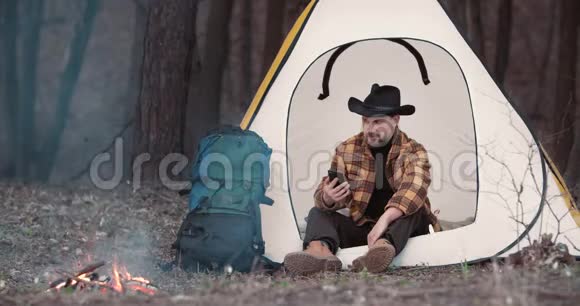 森林营地男性游客使用智能手机视频的预览图