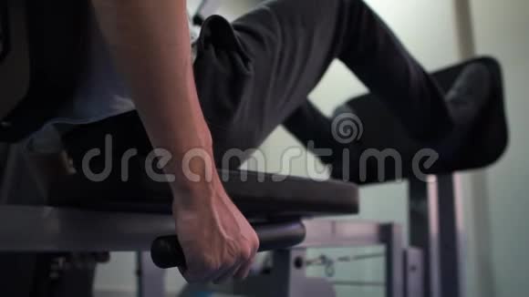 年轻男子坐着用他的腿在健身房里用金属盘子在邋遢视频的预览图