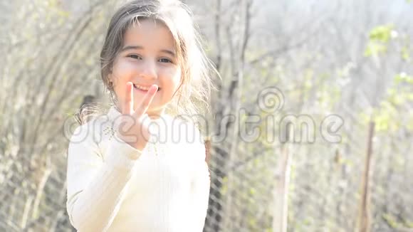 特写一个快乐的小女孩的肖像直视镜头用右手数数字视频的预览图