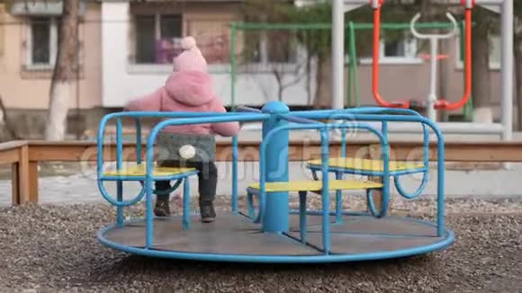 孤独的小女孩从儿童游乐场的旋转木马上下来视频的预览图