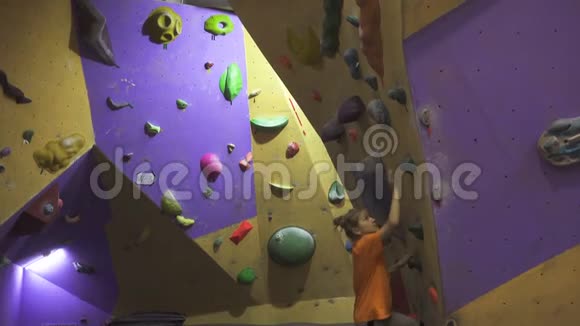 活跃的女孩爬在室内巨石墙上视频的预览图