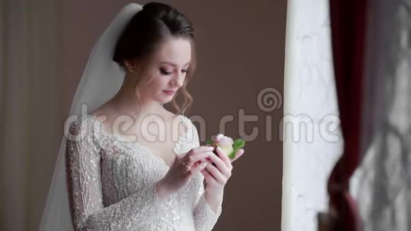 幸福的新娘看着新郎的婚礼对着窗户微笑晨曦从窗户落下视频的预览图