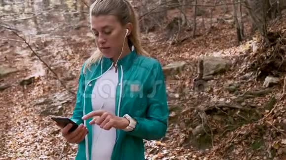 在秋天的早晨运动的年轻女子在山上跑步后一边用手机一边放松视频的预览图